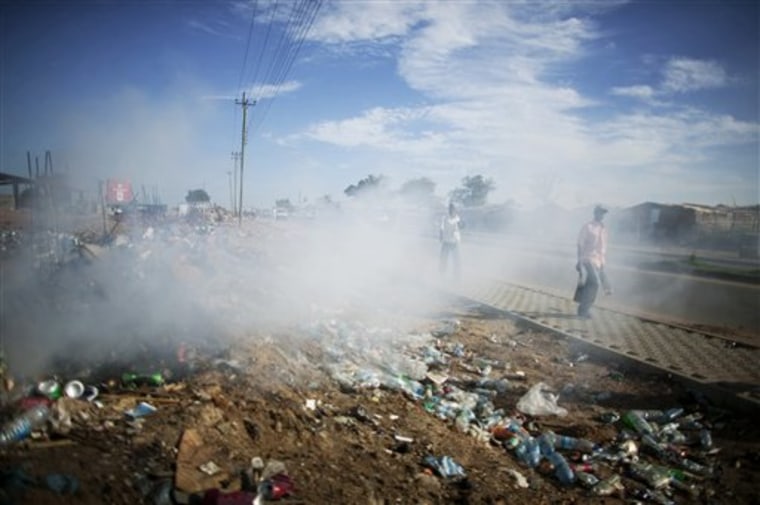 Residents walk past burning garbage on a newly constructed sidewalk in Juba, southern Sudan. In eight months, Juba will probably become the capital of the world's newest country, and one of its poorest and least educated. 